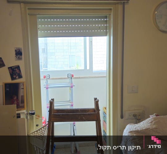 סולם מול חלון עם תריס גלילה פתוח